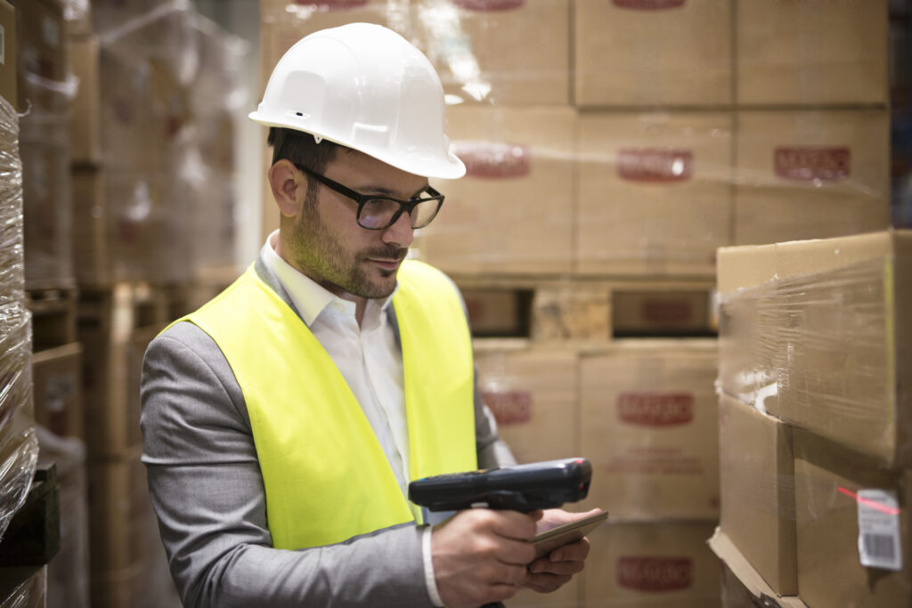 A warehouse worker scanning the label on a parcel with a handheld reader.